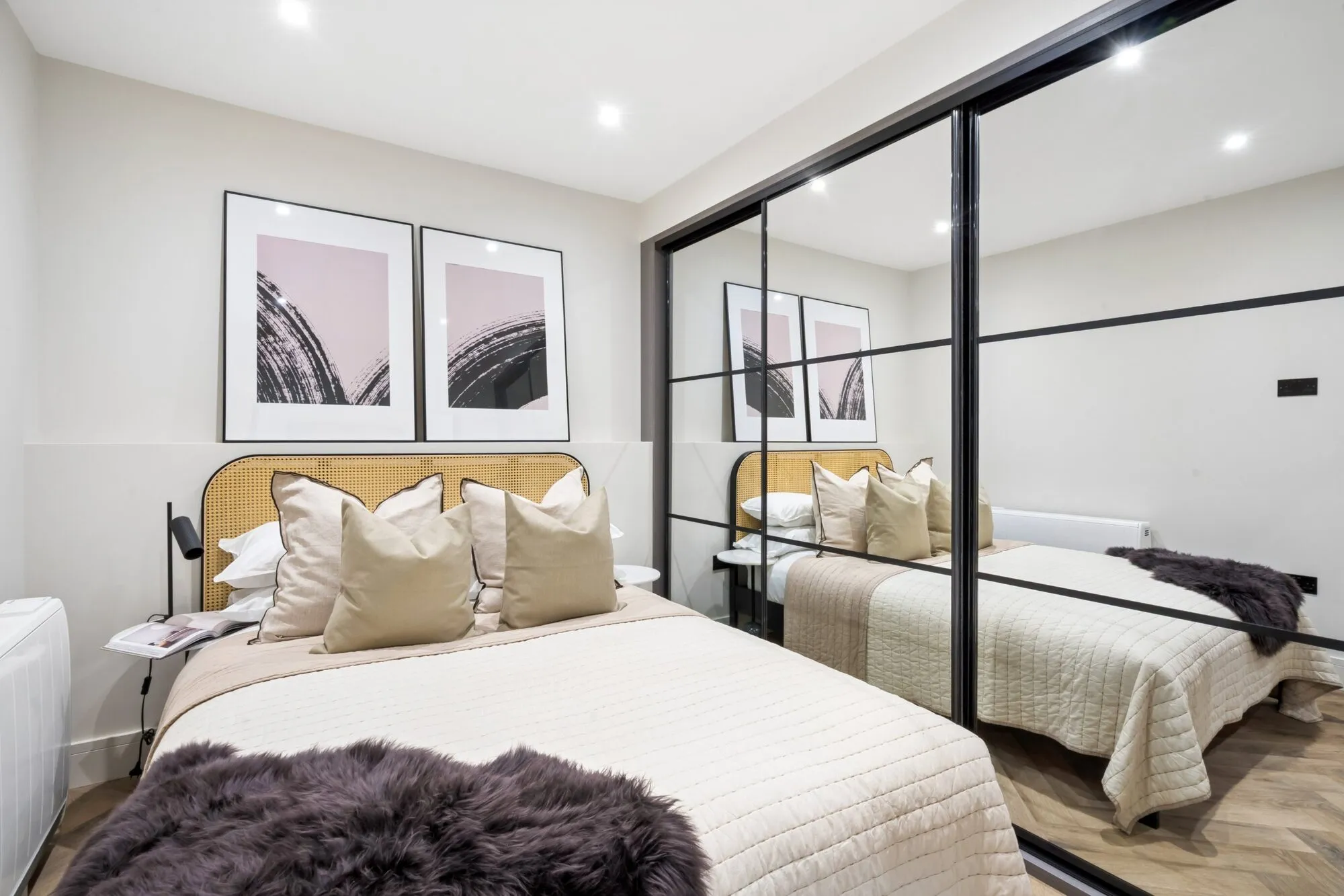 Bedroom in the show apartment with a double bed and mirrored sliding wardrobe doors.
