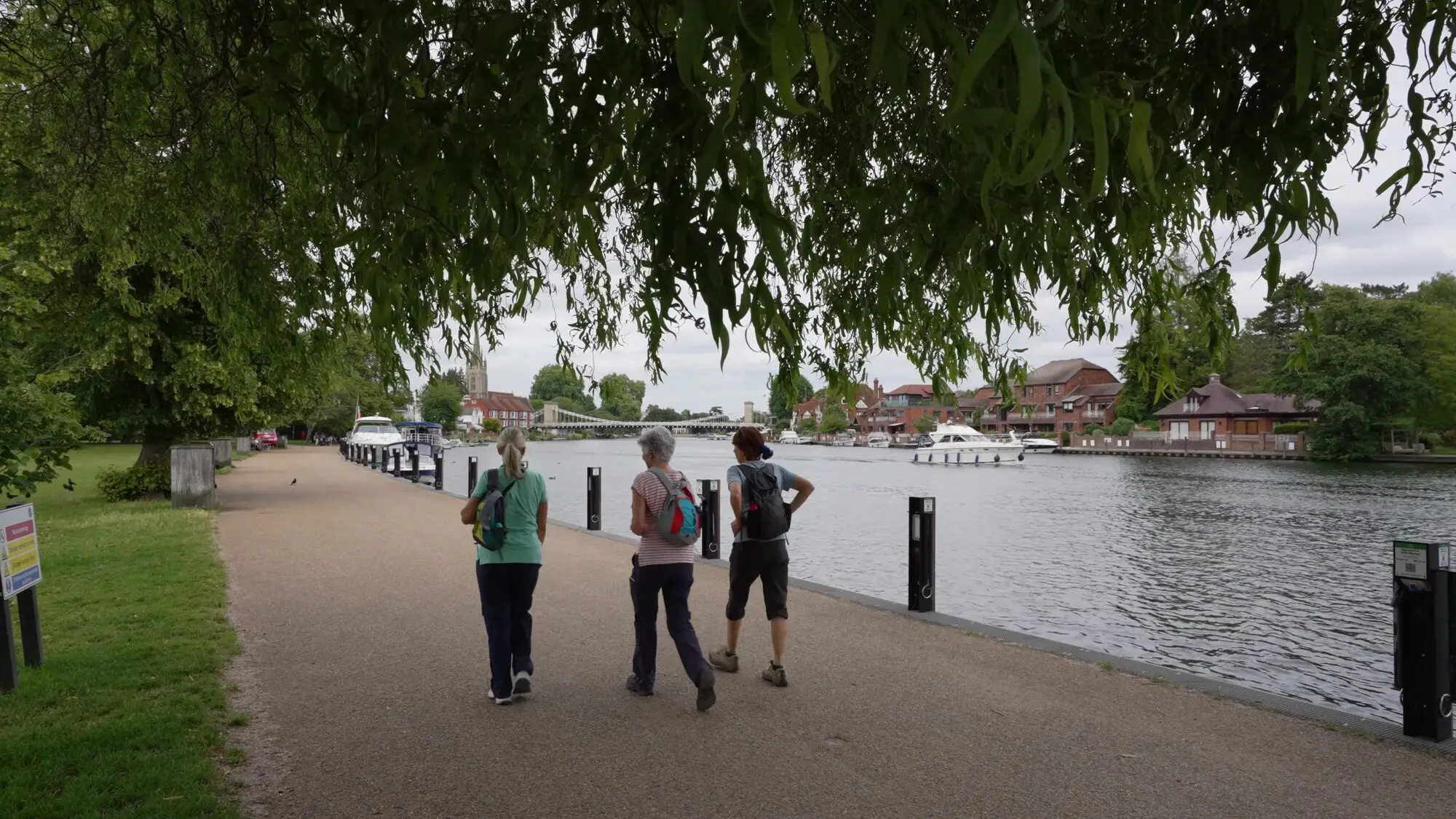 Walkers on the Thames path in Marlow, with boats moored along the river.